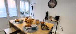 a table with food and drinks and a clock on the wall at "Modern Cosy" Hyper centre in Bernay