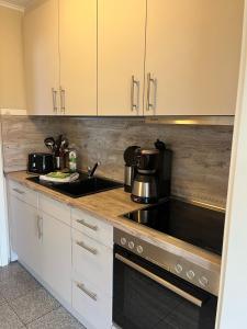 a kitchen with white cabinets and a stove top oven at Haus Seeschwalbe - Wohnung 07 in Spiekeroog