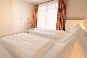 two white beds in a room with a window at Haus Seeschwalbe - Wohnung 15 in Spiekeroog +7 photos