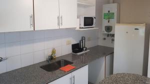 a kitchen with a sink and a white refrigerator at Hornera Italia - Céntrico, práctico y luminoso in Rosario +2 photos