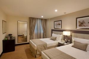 a hotel room with two beds and a mirror at Miramar By Windsor Copacabana in Rio de Janeiro