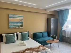 a bedroom with a bed and a blue chair at Стаи за гости Бела in Ahtopol