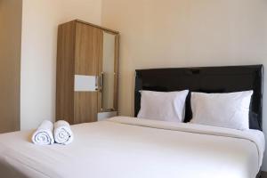 ein Schlafzimmer mit einem großen weißen Bett mit zwei Handtüchern darauf in der Unterkunft Brand New Studio at Tokyo Riverside PIK 2 Apartment By Travelio in Rawalembang