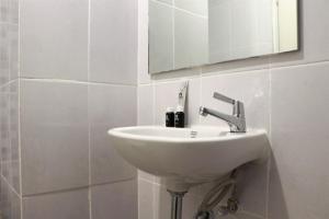 ein weißes Waschbecken in einem Badezimmer mit einem Spiegel in der Unterkunft Brand New Studio at Tokyo Riverside PIK 2 Apartment By Travelio in Rawalembang + 1 Foto