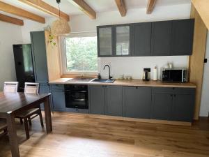 a kitchen with black cabinets and a wooden table at Domek na Zagórze - domek całoroczny in Krasnobród +13 photos