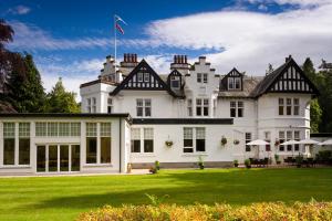 ein großes weißes Haus mit grünem Rasen in der Unterkunft Pine Trees Hotel Pitlochry in Pitlochry