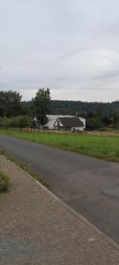 a road next to a field with a building in the background at Haus Am Teich Oetjens in Weilburg_Gaudernbach