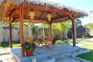 a patio with a table and chairs under a thatch roof at Résidence Oriole in Hell-Ville