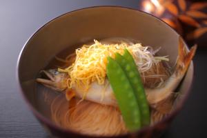 a bowl of soup with noodles and cheese and a fish at Koorogirou in Kaga