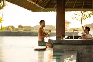 two men sitting in the water in a swimming pool at Holiday Inn Resort Bali Canggu by IHG in Canggu