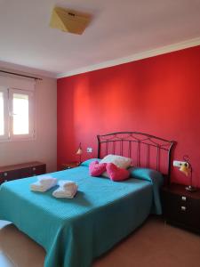 1 dormitorio con paredes rojas y 1 cama con 2 toallas en Apartamentos San Miguel 2, en Almerimar