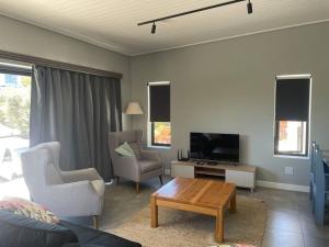 a living room with a tv and two chairs and a table at Cola Beach Nomads Nook in Sedgefield