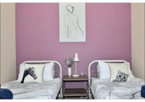 2 Betten in einem Zimmer mit lila Wänden in der Unterkunft Cozy Mountain Cottage in Katoomba