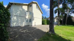 a white house with a tree in front of it at Family Apartments in Jūrmala