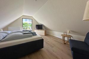Un dormitorio con una cama, un televisor y una silla. en Ferienwohnung Käte, en Warnemünde 7 fotos más