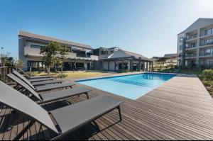 a swimming pool with lounge chairs next to a building at Ballito Escape in Ballito
