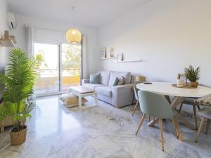 ein weißes Wohnzimmer mit einem Tisch und einer Couch in der Unterkunft Cubo's Apartment Sol Andalusi in Alhaurín de la Torre