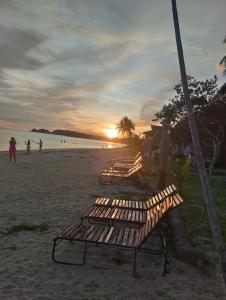 una fila de bancos en una playa al atardecer en Ban Tai Bay Bungalows, en Ko Pha Ngan