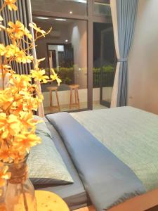 une chambre avec un lit et un vase avec des fleurs jaunes dans l'établissement Sunshine villa, à Ấp Long Hồ Hạ