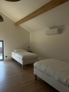 two beds in a room with white walls and wooden floors at Gîte de Condeiss in Condeissiat