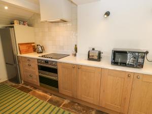 a kitchen with a stove and a microwave at Cobbles Cottage in Heptonstall +18 photos