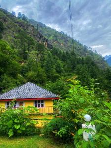 a small yellow house in the middle of a mountain at Canvas and Coffee in Kasol