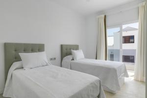 a bedroom with two beds with white sheets and a window at Dúplex El Equilibrio in Playa Honda
