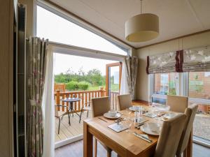 a dining room with a table and a large window at Lodge 26, Fishing Lakes in Stowmarket