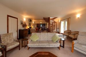 a living room with couches and chairs and a staircase at Blarghour Farm Cottages in Ardchonnell