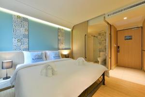 a bedroom with a large white bed and a bathroom at Kastel Bangkok Hotel in Bangkok