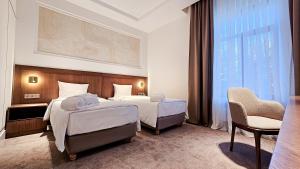a hotel room with two beds and a chair at Grand Tien Shan Hotel in Almaty +55 photos