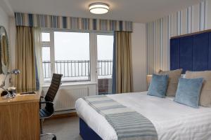 a hotel room with a bed and a desk and window at Best Western Princes Marine Hotel in Brighton & Hove
