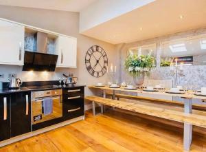 a kitchen with a long table and a large clock on the wall at Barn near york with hot tub in York