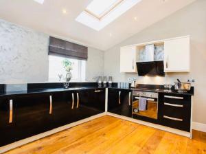 a kitchen with black and white cabinets and wood floors at Barn near york with hot tub in York