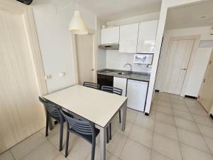 uma cozinha com uma mesa e cadeiras brancas em Apartamentos Maria Victoria em Benidorm
