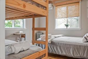 two bunk beds in a room with two windows at Pocono Scandinavian Cottage in Tobyhanna