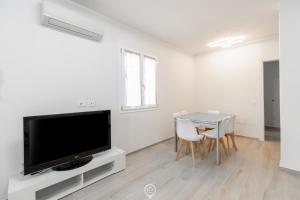 ein Wohnzimmer mit einem TV und einem Tisch mit Stühlen in der Unterkunft White Magnolia Apt in Oristano + 23 Fotos