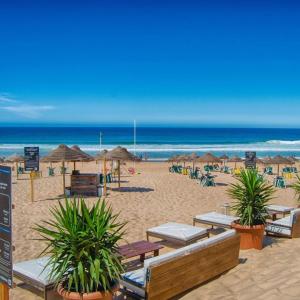 a beach with chairs and umbrellas and the ocean at House Caparica in Costa da Caparica