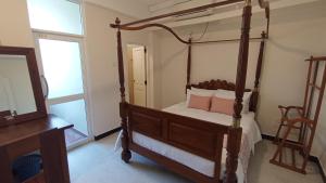 a bedroom with a four poster bed with a mirror at City Nest Inn in Kandy