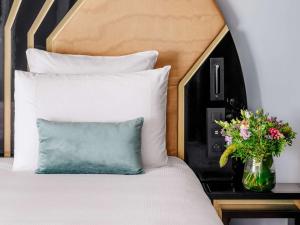a bed with a blue pillow and a vase of flowers at The 1932 Hotel & Spa Cap d'Antibes - MGallery Collection in Juan-les-Pins