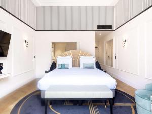 a bedroom with a large white bed and a blue rug at The 1932 Hotel & Spa Cap d'Antibes - MGallery Collection in Juan-les-Pins