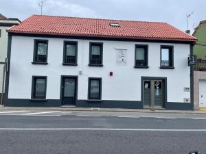 a white building with black windows and a red roof at Pensión Casa de Casiano en Esteiro in Muros +4 photos