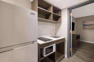 a small kitchen with a sink and a refrigerator at Suburban Studios Milwaukee Airport in Milwaukee