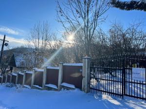 a fence covered in snow with the sun behind it at Casa Din Deal in Podişu