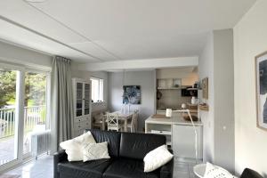 ein Wohnzimmer mit einer schwarzen Couch und einer Küche in der Unterkunft Zeearend in Cadzand
