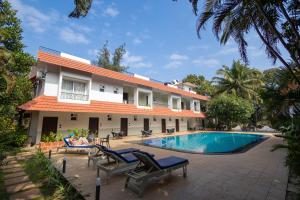 a person laying on a chair next to a building with a swimming pool at Anjuna Blue Resort in Anjuna