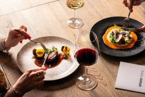 a table with two plates of food and a glass of wine at Urban Creme in Prague