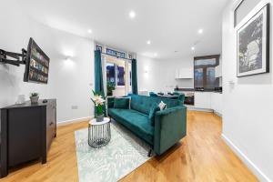 a living room with a green couch and a kitchen at Comfy Flat in Staines in Staines upon Thames
