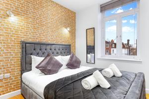 a bedroom with a large bed with a brick wall at Comfy Flat in Staines in Staines upon Thames