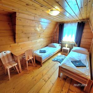 ein Schlafzimmer mit 2 Betten und einem Tisch in einer Blockhütte in der Unterkunft Pokoje pod Brzozami - zniżki na Termy i Rowery ! in Czarna Góra